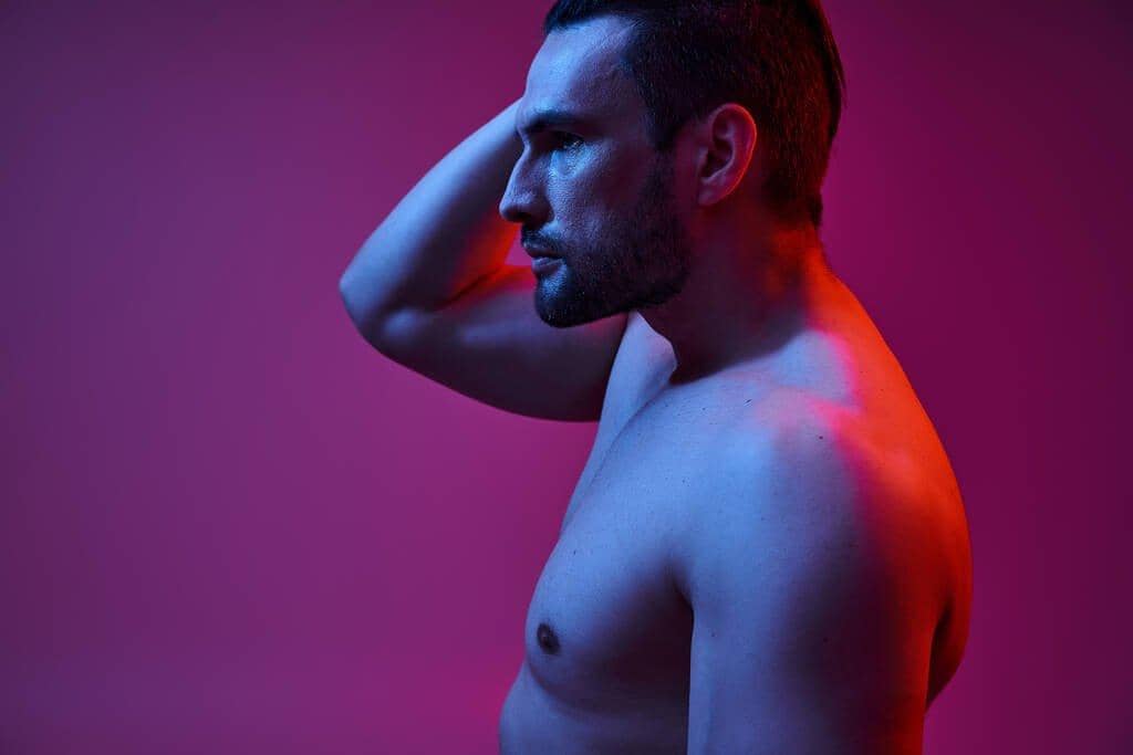Fragile Masculinity: The Root of Controlling Behavior in Relationships 4 seductive muscular man bristle posing hand head purple background