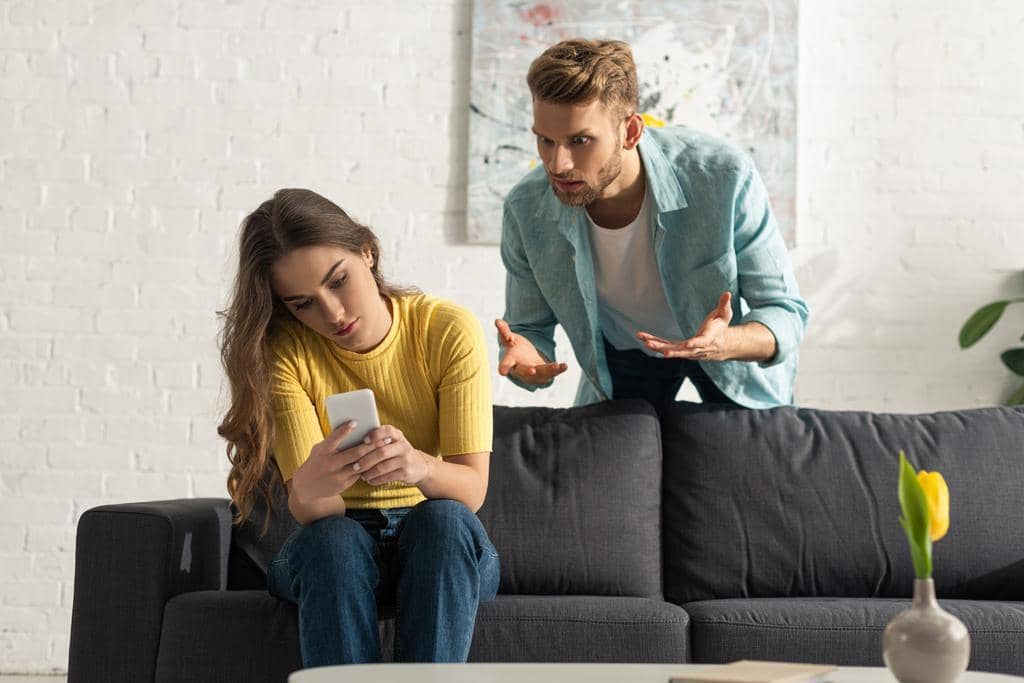 11 Surprising Selfish Things Women Do in Relationships - According to Men 10 angry-man-quarreling-smartphone-depended-girlfriend-couch