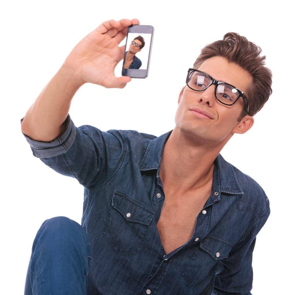 Narcissism Uncovered: 10 Toxic Traits of a Narcissist You Can’t Ignore 8 casual young man sitting on the floor and taking a picture of himself with his phone. isolated on white