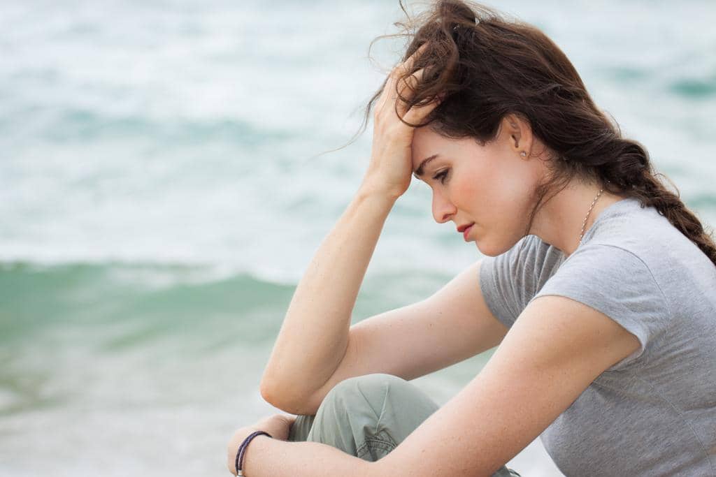 My Partner Abuses Me When I'm Already Hurting 9 Close-up of a sad and depressed woman deep in thought outdoors.