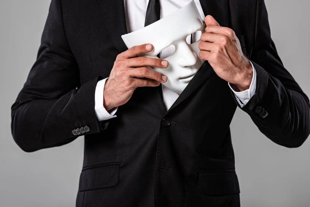 Machiavellianism in Relationships: 4 Helpful Ways to Handle It 2 partial view businessman black suit holding white mask isolated grey