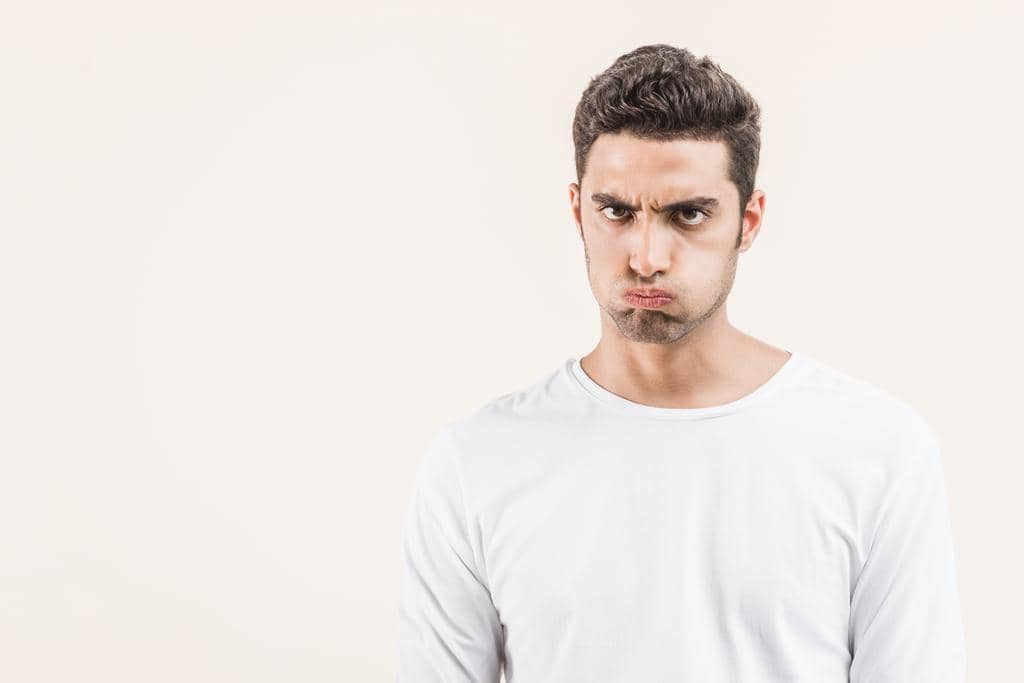 Male Fragility and Abusive Relationships: The Psychological Underpinnings 6 angry young man blowing cheeks looking camera isolated beige