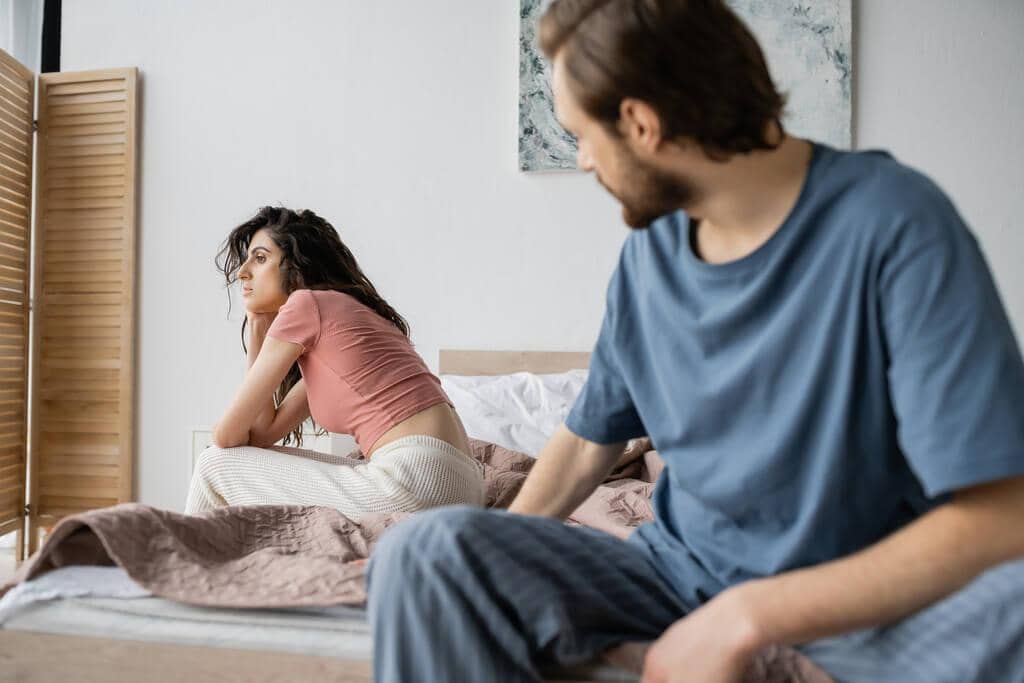 50 Painful Signs of an Emotionally Unavailable Husband 8 indifferent woman pajama sitting bed blurred boyfriend home