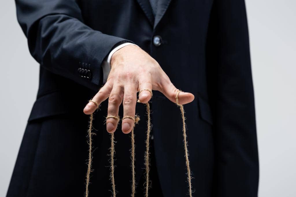 9 Fake Alpha Male Traits: Eye-Opening Ways to Spot a Phony 10 stock photo partial view puppeteer suit strings fingers isolated grey
