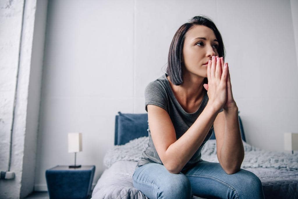 5 Easy Tricks to Calm Your Anxious Mind Anytime 2 depressed woman sitting bed covering mouth home