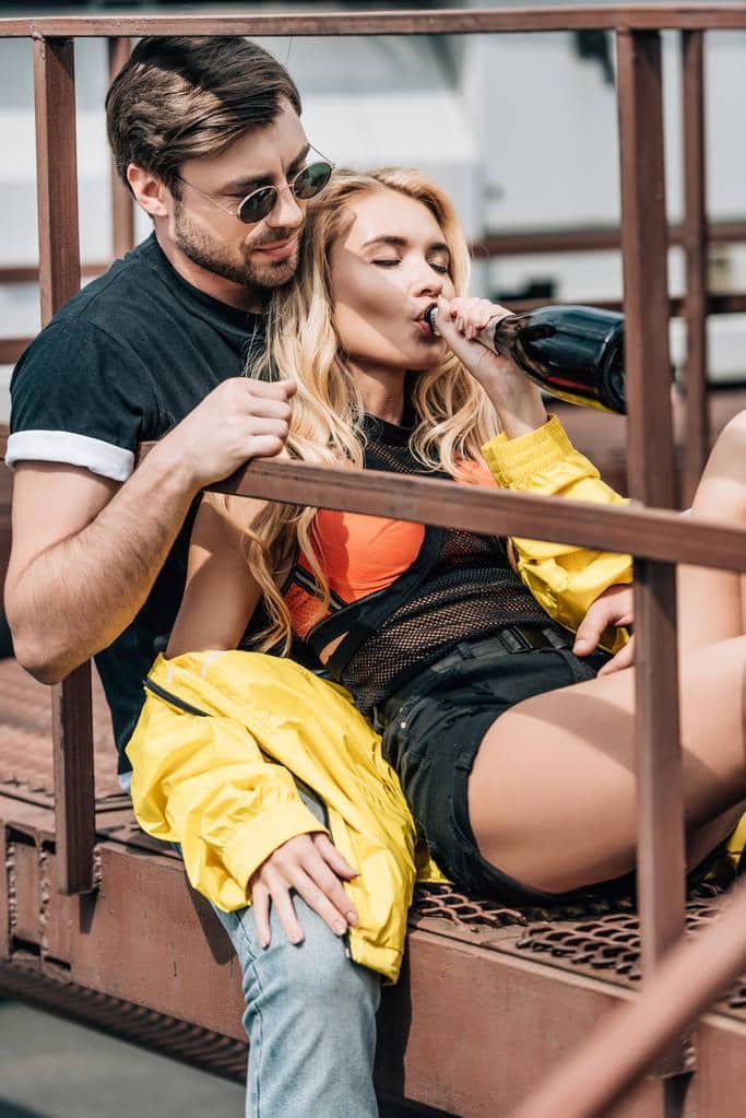 With One Partner Still Partying Can Your Relationship Thrive? 6 man glasses sitting stairs attractive woman drinking champagne