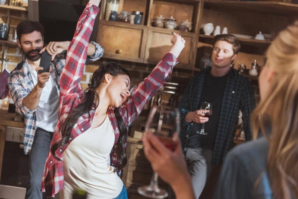 With One Partner Still Partying Can Your Relationship Thrive? 3 people having fun at home party