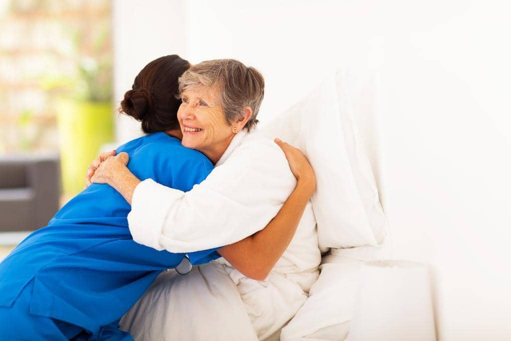 7 Devastating Financial Mistakes in Gray Divorce: How to Avoid Them 10 happy elderly woman hugging caregiver on bed