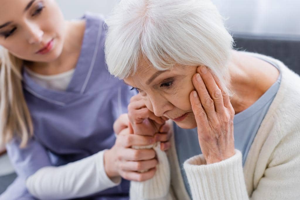 7 Devastating Financial Mistakes in Gray Divorce: How to Avoid Them 7 young nurse touching hand elderly woman suffering dementia sitting bowed