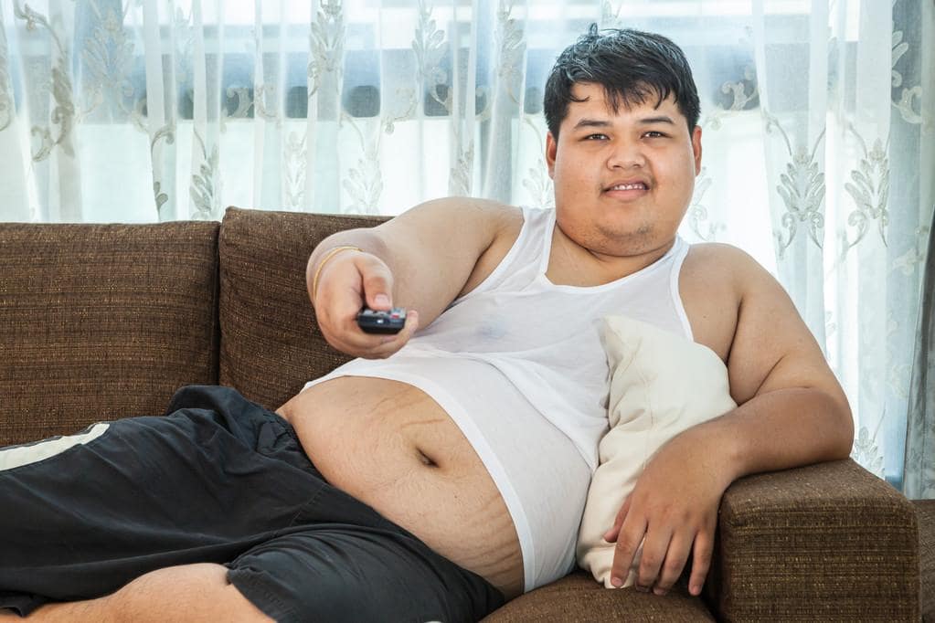 11 Types of Men Who Get Dumped: Brutal Reasons Women Leave 13 Overweight asian guy sitting on the couch with remote in hand trying to watch some TV