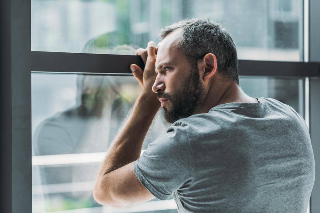 7 Burning Examples of Trauma Adaptation in Relationships 6 upset bearded man leaning window looking