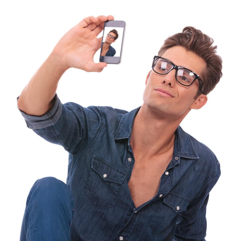 Narcissism Uncovered: 10 Toxic Traits of a Narcissist You Can’t Ignore 8 casual young man sitting on the floor and taking a picture of himself with his phone. isolated on white