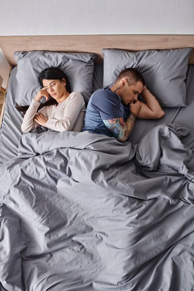 10 Brutally Honest Reasons Men Ignore Wives' Unhappiness 6 high angle view depressed interracial couple lying bed home family