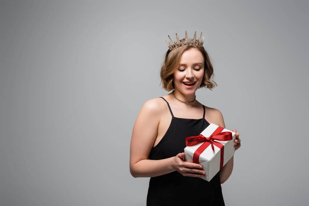 The Mystery of Princess Treatment: Who Gets It and Why 3 woman slip dress crown holding present isolated grey
