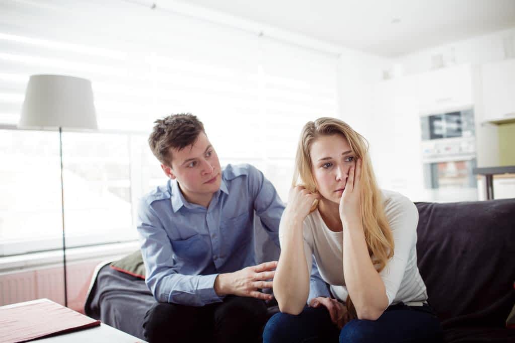 sad woman sitting on the couch with her boyfriend