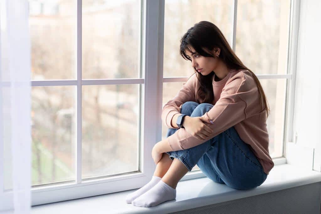 sad woman looking out of window at home 2