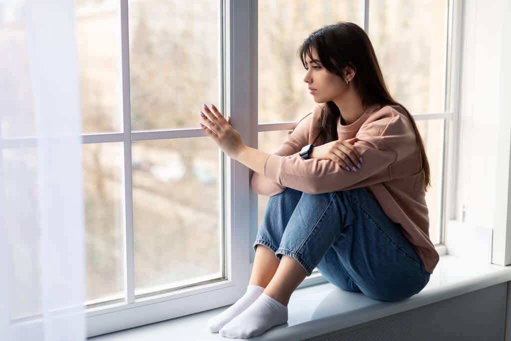 sad woman looking out of window at home