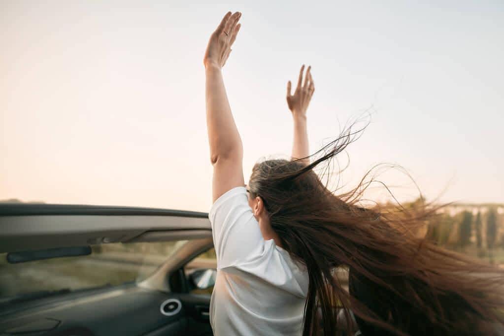 happy woman enjoying summer road trip convertible car she raises