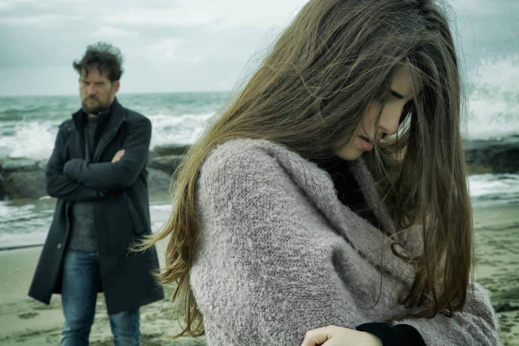 angry man looking sad girlfriend after fight in front of the ocean