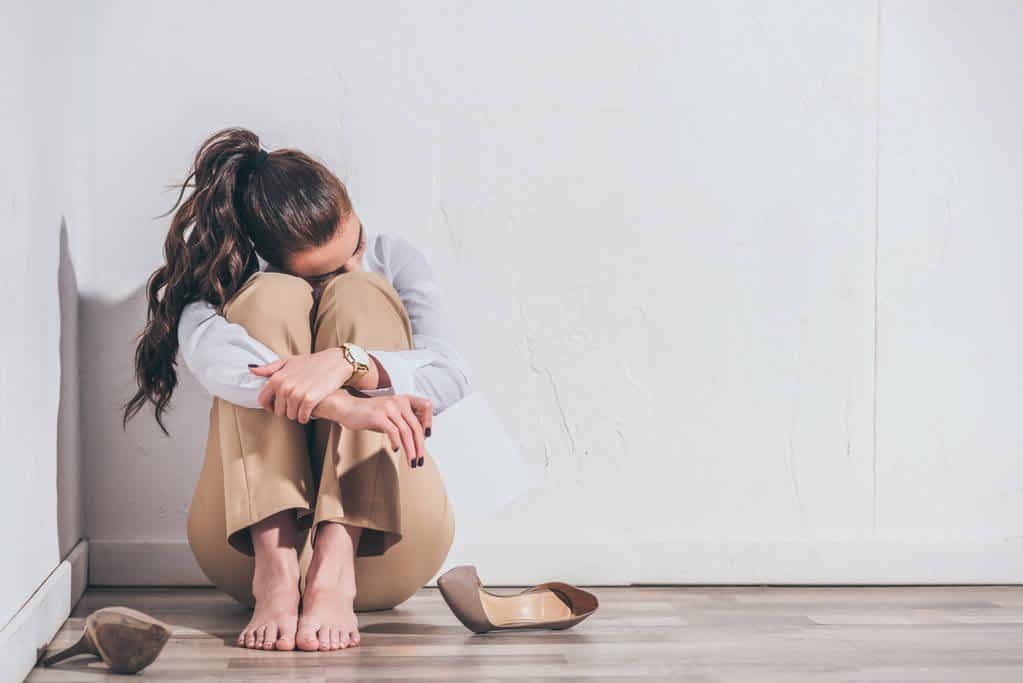 upset woman sitting floor holding photo white wall home grieving 1