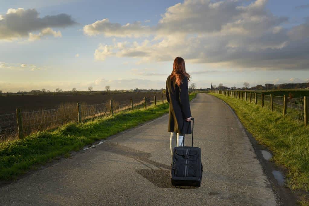 runaway girl standing with her suitcase on the road