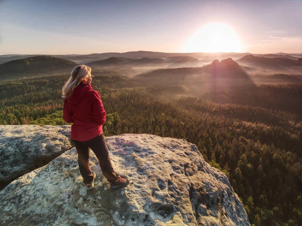 woman in outdoor clothes enjoy view at summit in mountains