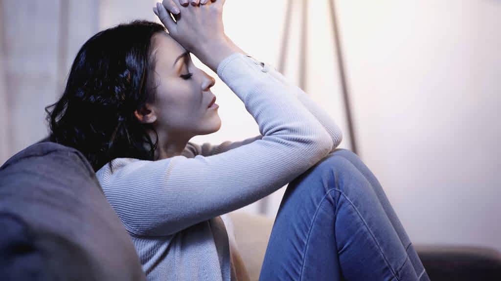 stock photo depressed woman casual clothes sitting sofa closed eyes holding clenched