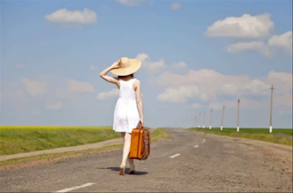 lonely girl with suitcase at country road