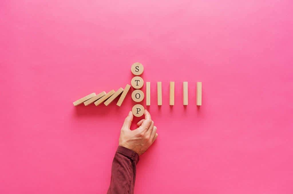 hand interrupting falling dominos