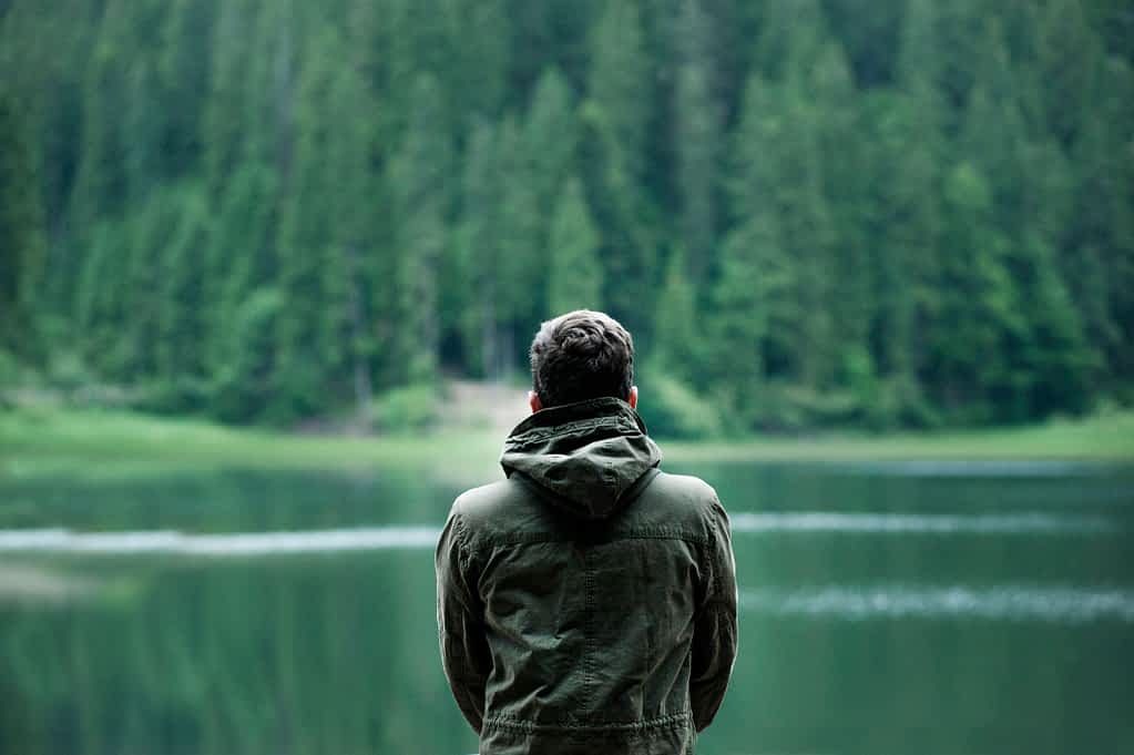 man looking out over a lake in the mountains