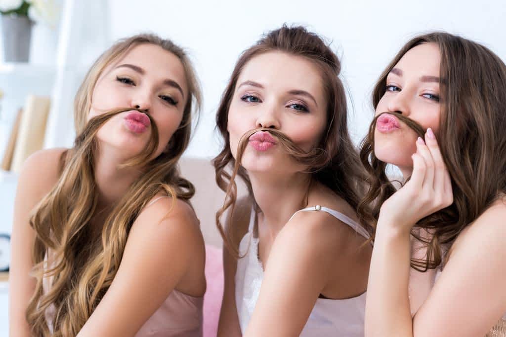 3 women friends making mustaches out of their hair