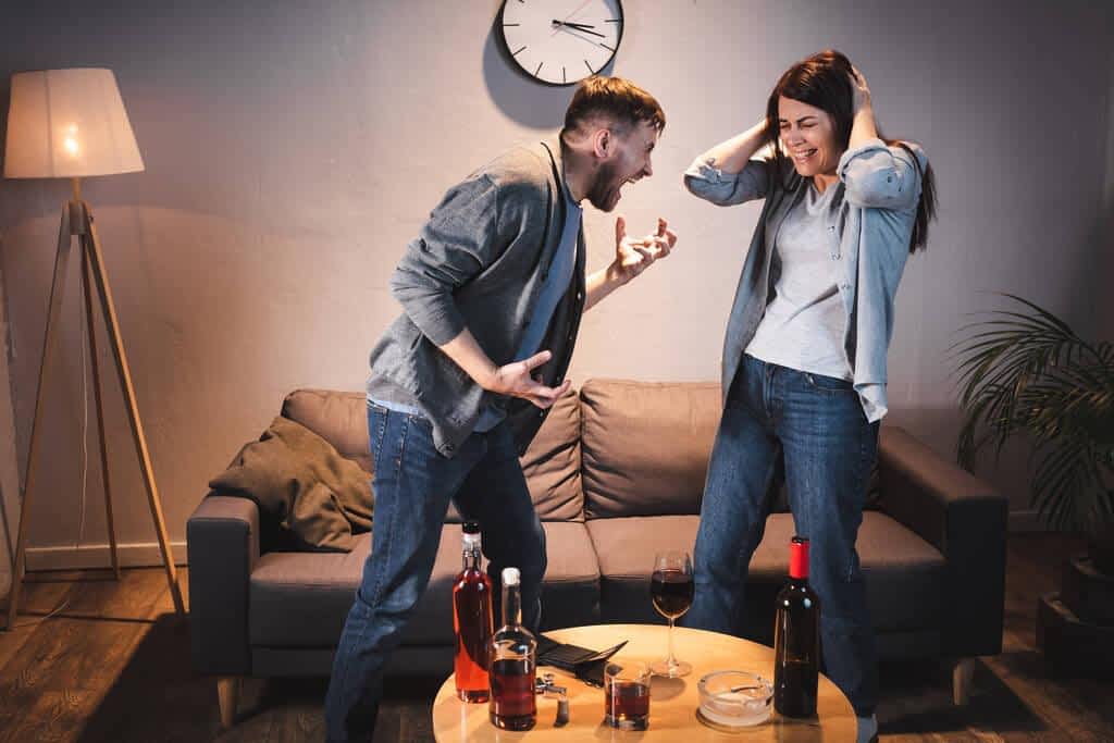drunk couple quarreling table bottles alcohol home