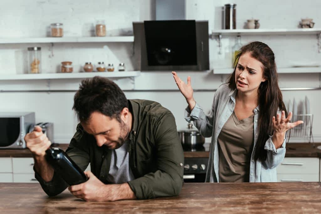 30 Ways to Protect Yourself From an Angry Drunk 11 worried woman quarreling alcohol addicted husband wine bottle kitchen