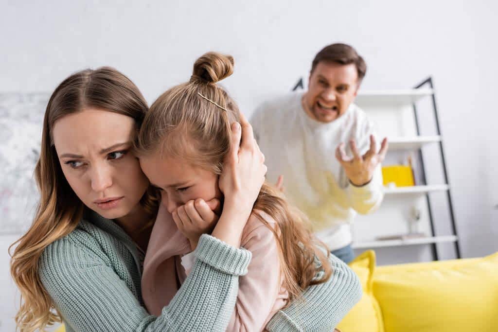 I Walked on Eggshells for 30 Years. Here's What I Wish I'd Known Sooner 3 woman hugging daughter while angry husband screaming 1