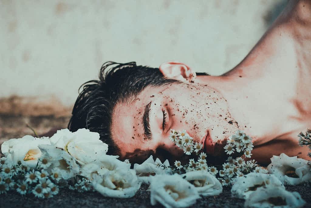 depressed man laying down in flowers