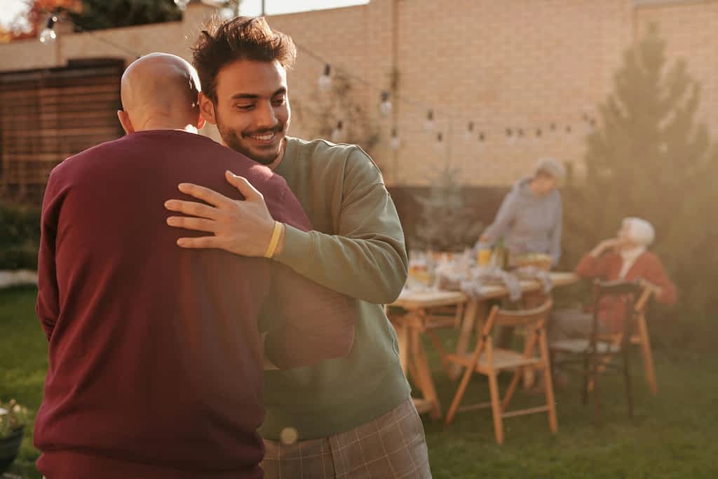 Man hugs another man at a backyard party