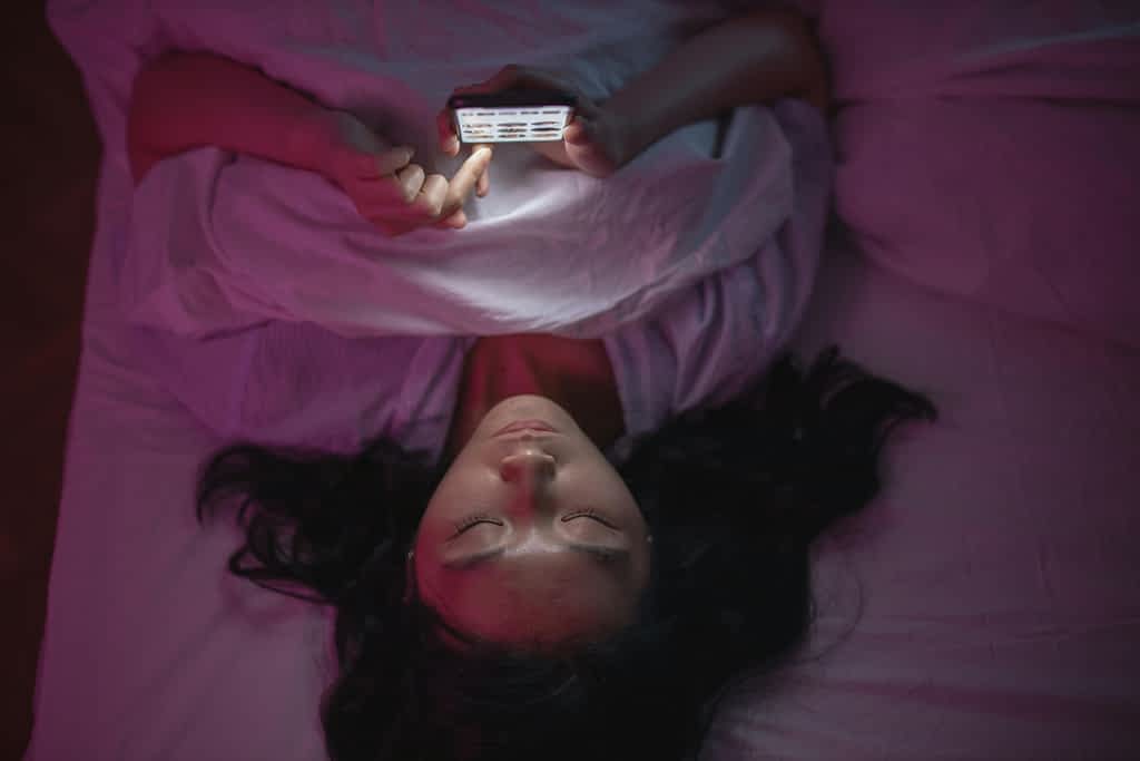 woman texting late at night in bed