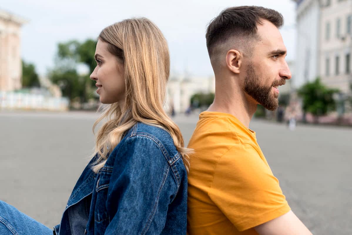 couple sitting back to back symbolic of How to Detach From a Man Emotionally
