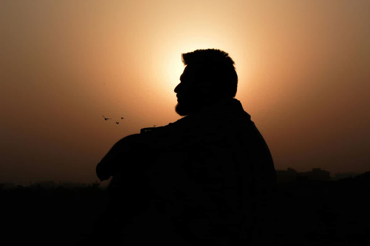silhouette of a man at sitting down alone at sunset