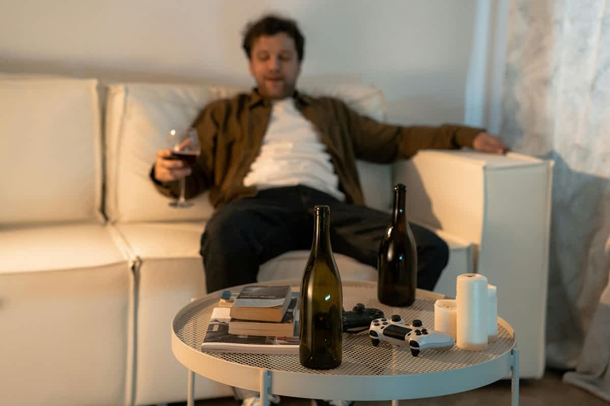 man sits drinking on a sofa