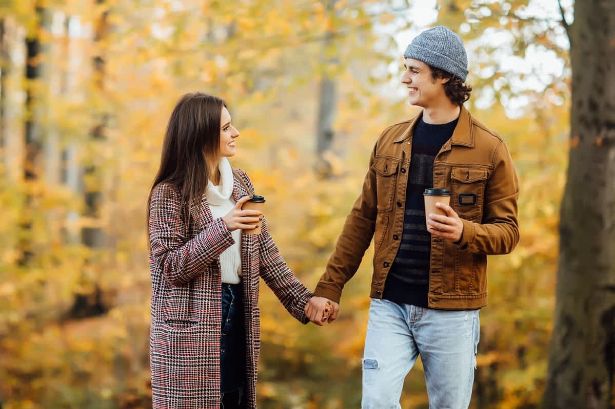 Couple in love holding cups of tea or coffee and holding hands.