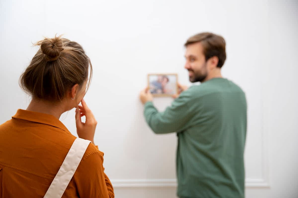 man hanging a small picture on the wall