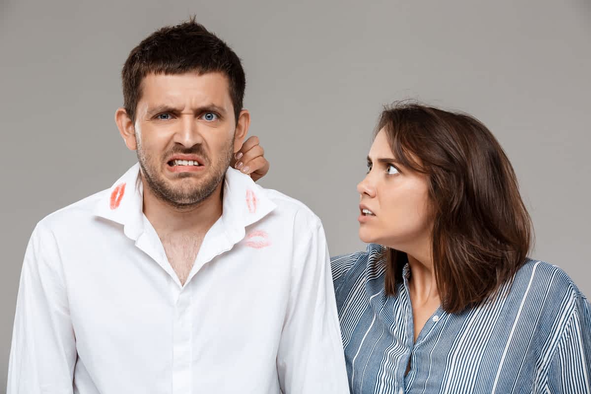 Woman angry at cheating man with lipstick on his collar