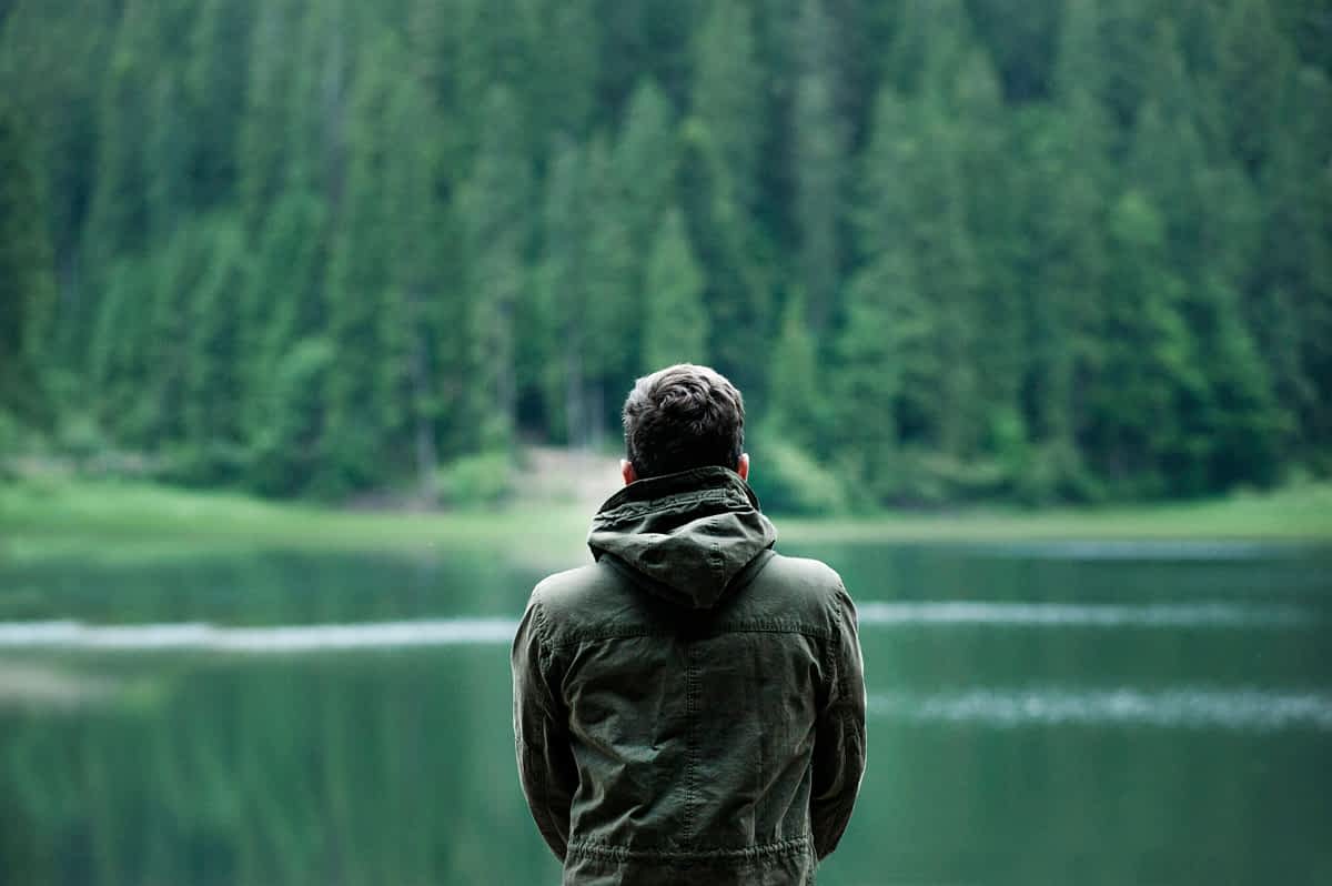 man looking out over a lake in the mountains