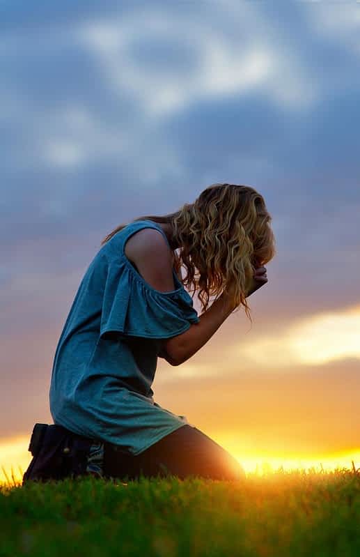 broken woman praying at sunset