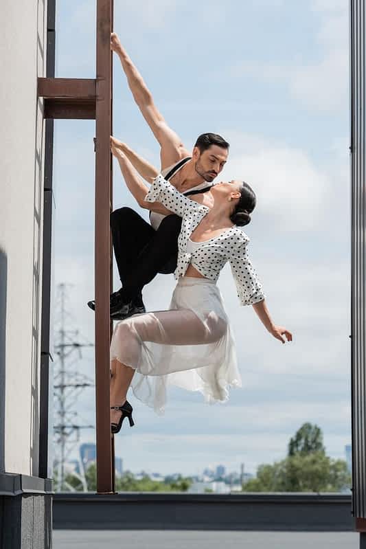 professional dancers kissing while posing ladder rooftop building daytime