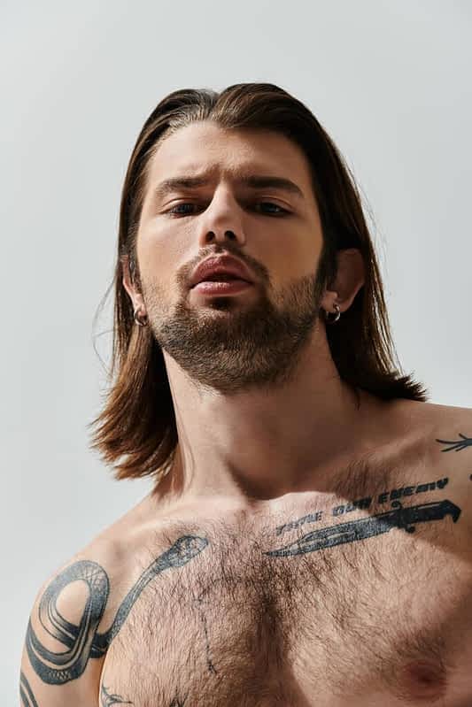 stylish caucasian man long hair showcases intricate chest tattoos