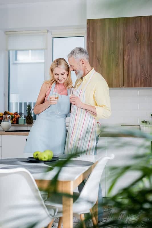 Why Marriage Gets Harder After 50: 9 Unique Challenges 11 positive mature man apron holding champagne wife apron kitchen