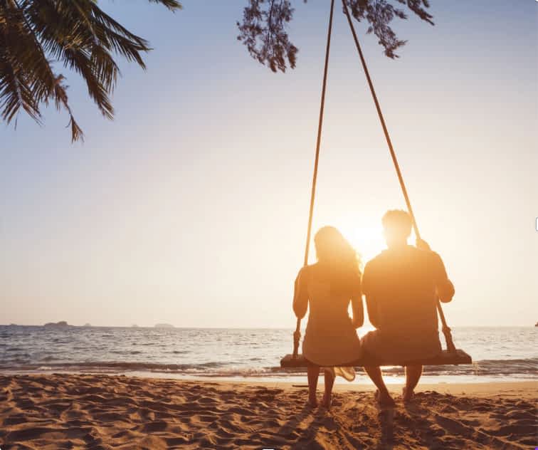couple sitting on a swing together at sunset