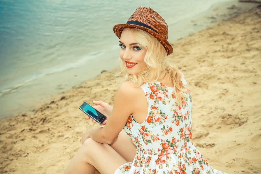 Why Men Mistake Kindness For Flirting 8 woman on beach with smartphone